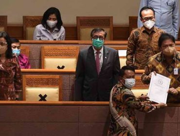 Menko Perekonomian Airlangga Hartarto (kanan) didampingi Menkumham Yasonna Laoly (kedua kiri) dan Menteri Keuangan Sri Mulyani (kiri) menerima laporan akhir dari Ketua Badan Legislasi DPR Supratman Andi (bawah) saat pembahasan tingkat II RUU Cipta Kerja pada Rapat Paripurna DPR di Kompleks Parlemen, Jakarta, Senin (5/10/2020). ANTARA FOTO/Hafidz Mubarak A/pras