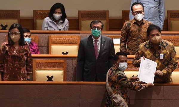 Menko Perekonomian Airlangga Hartarto (kanan) didampingi Menkumham Yasonna Laoly (kedua kiri) dan Menteri Keuangan Sri Mulyani (kiri) menerima laporan akhir dari Ketua Badan Legislasi DPR Supratman Andi (bawah) saat pembahasan tingkat II RUU Cipta Kerja pada Rapat Paripurna DPR di Kompleks Parlemen, Jakarta, Senin (5/10/2020). ANTARA FOTO/Hafidz Mubarak A/pras